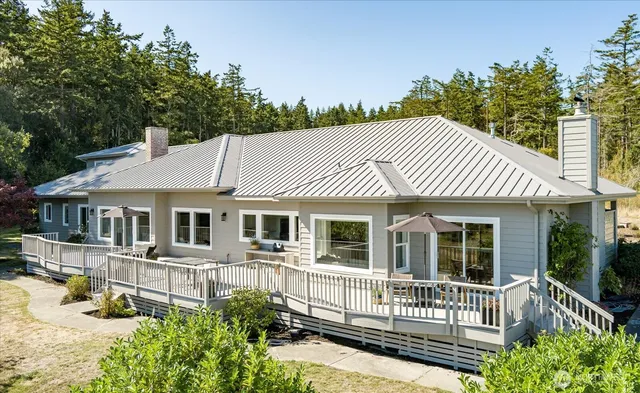 a view of a white house with large windows and a small yard