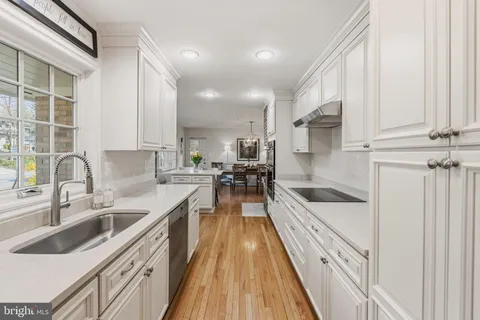 a kitchen with stainless steel appliances granite countertop a refrigerator a stove and a dining table with wooden floor