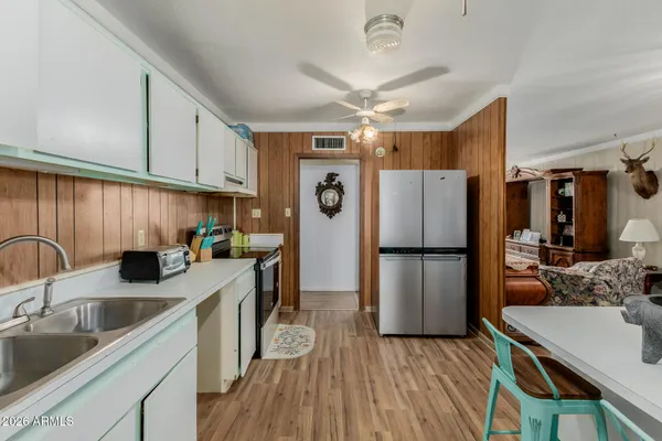 a kitchen with a sink a refrigerator a stove and white cabinets with wooden floor