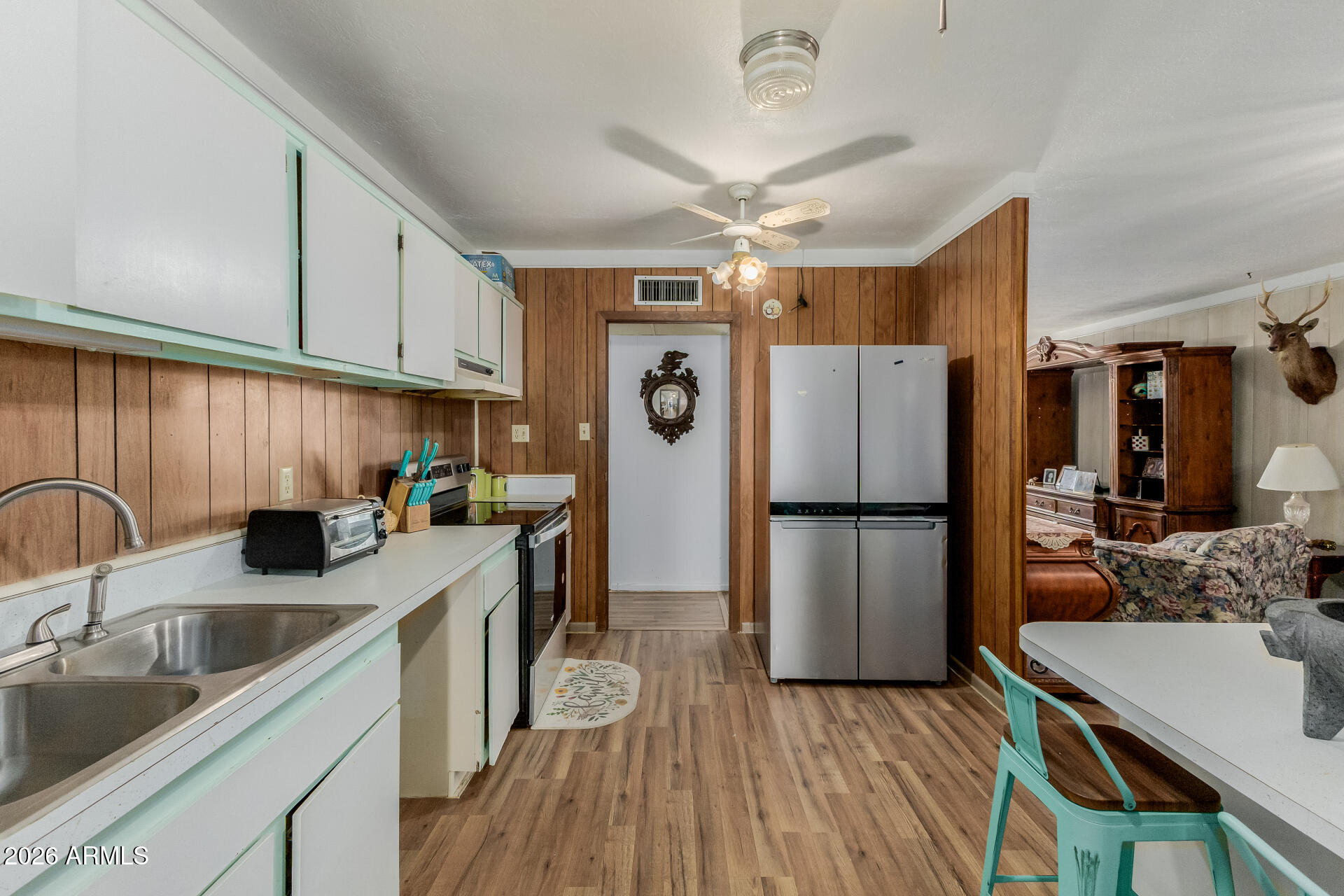 420 West 6th Street Ajo, AZ 85321 - Photo 11 of 35 a kitchen with a sink a refrigerator a stove and white cabinets with wooden floor