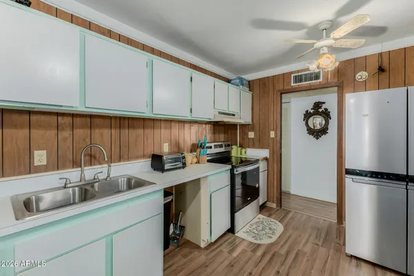 a kitchen with stainless steel appliances granite countertop a refrigerator a sink dishwasher a stove with wooden cabinets and floors