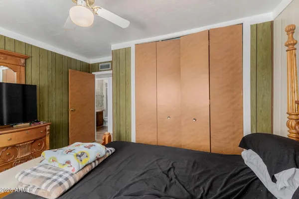 a bedroom with a bed and a flat tv screen on dresser