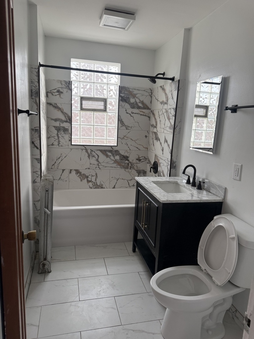 8204 South Elizabeth Street, Unit 2 Chicago, IL 60620 - Photo 9 of 11 a bathroom with a bathtub sink mirror vanity and toilet