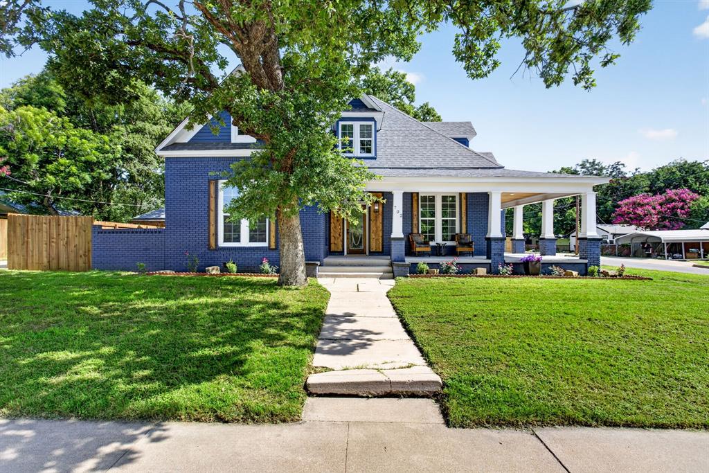 702 West Spring Street Weatherford, TX 76086 - Photo 4 of 39 Blue brick exterior with white trim, a covered front porch, dormer windows, and a mature tree