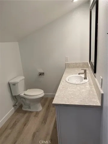 a bathroom with a granite countertop toilet a sink and a mirror
