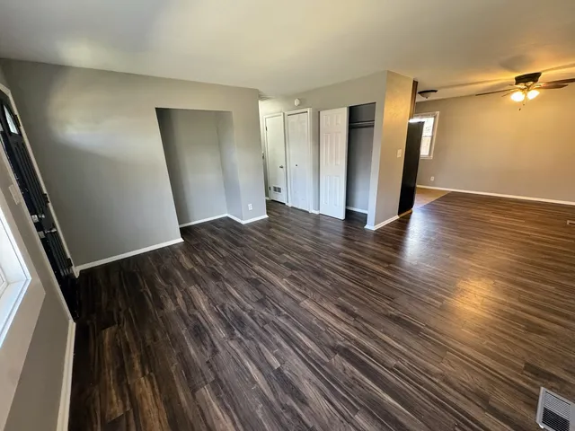 a view of an empty room with wooden floor and a window