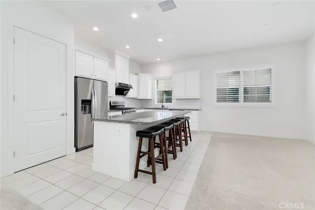 a kitchen with stainless steel appliances granite countertop a refrigerator and a stove top oven