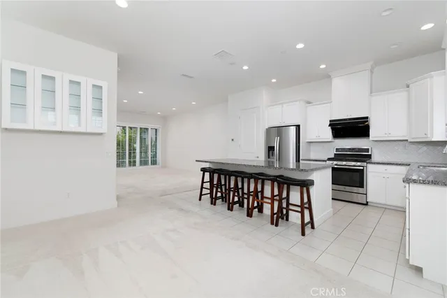 a kitchen with stainless steel appliances kitchen island granite countertop a stove a sink a microwave a dining table and chairs