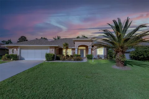 a view of a white house with a big yard and potted plants