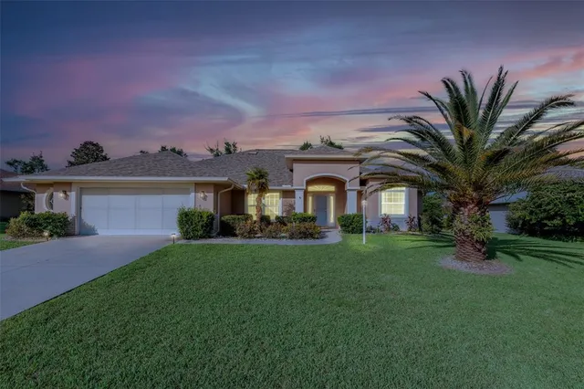 a view of a white house with a big yard and potted plants