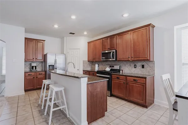 a kitchen with stainless steel appliances granite countertop a stove top oven a sink dishwasher and a refrigerator