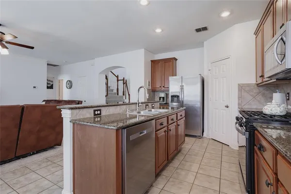 a kitchen with stainless steel appliances granite countertop a sink and a refrigerator