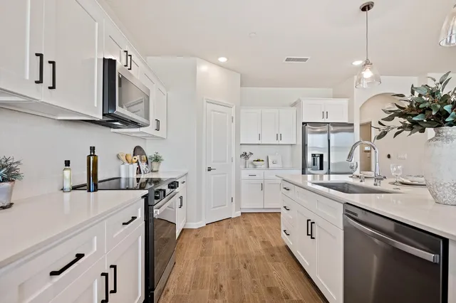 a kitchen with stainless steel appliances granite countertop a sink a stove and a refrigerator
