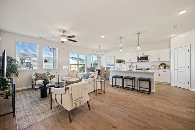 a living room with furniture kitchen view and a wooden floor