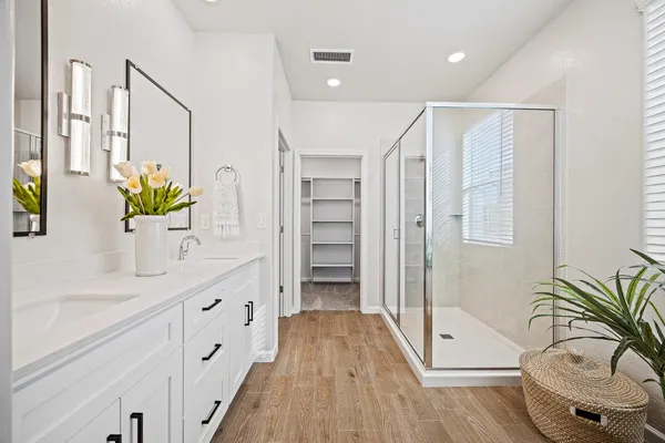 a spacious bathroom with a granite countertop sink a glass door shower and a mirror