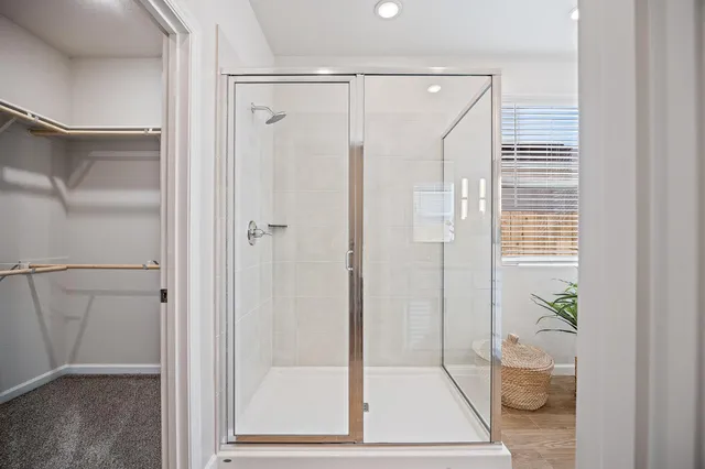 a bathroom with a glass shower door and a window