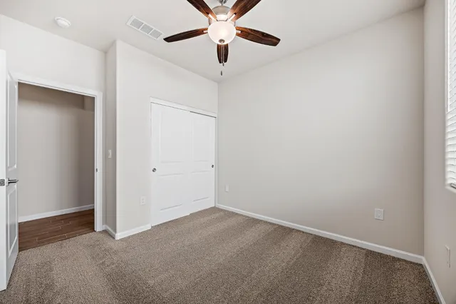 an empty room with closet and a chandelier fan