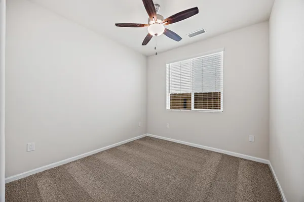 an empty room with a window and a fan