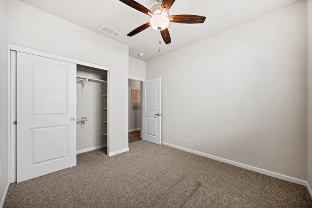an empty room with closet and a ceiling fan