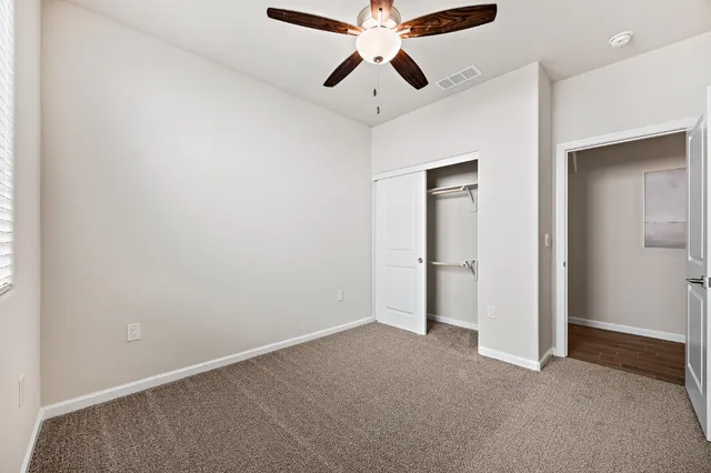 a view of an empty room and chandelier fan