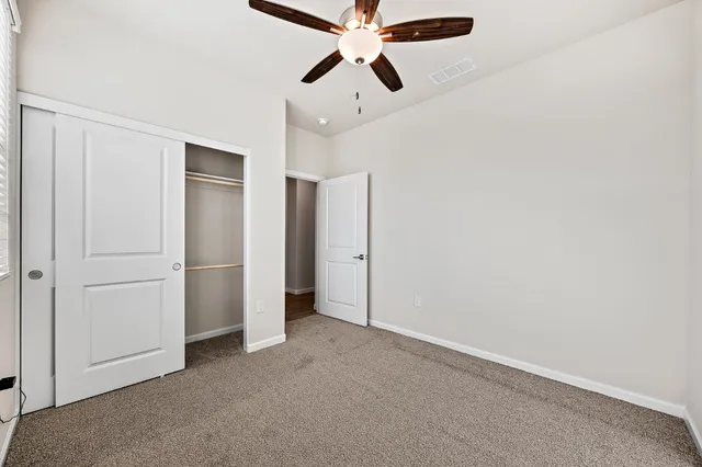 an empty room with closet and a ceiling fan