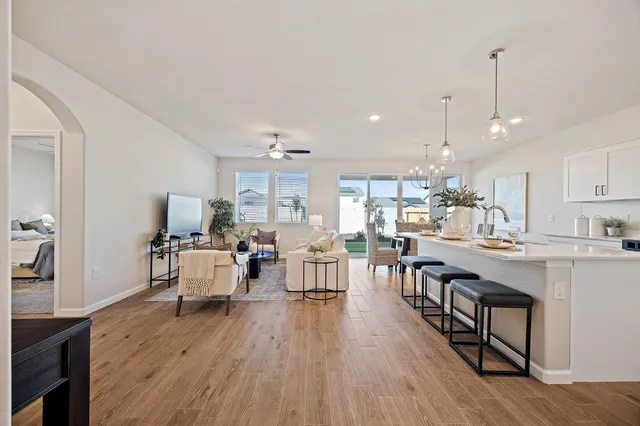 a view of a dining room and livingroom with furniture wooden floor a chandelier