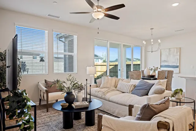 a living room with furniture kitchen view and a chandelier