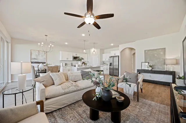 a living room with furniture a rug kitchen view and a chandelier