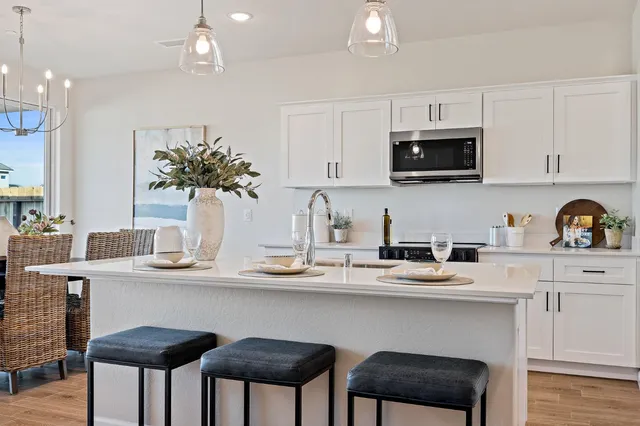 a kitchen with stainless steel appliances a table chairs refrigerator and microwave