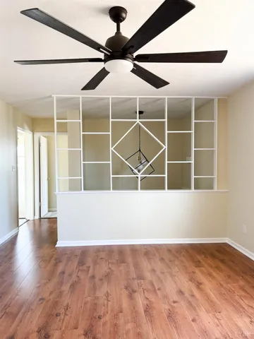 a view of an empty room with wooden floor and a window