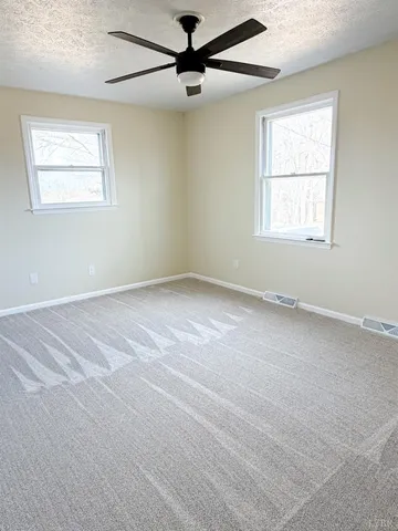 an empty room with a window and a fan