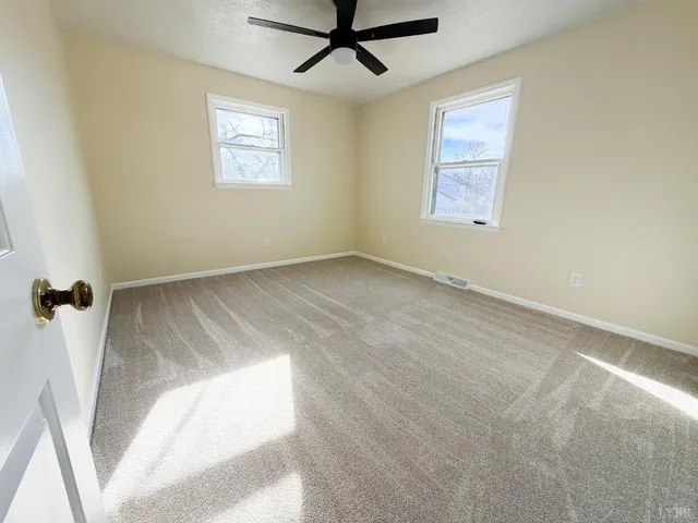 an empty room with windows and fan