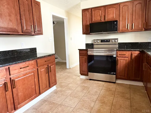 a kitchen with granite countertop a stove and a microwave with cabinets