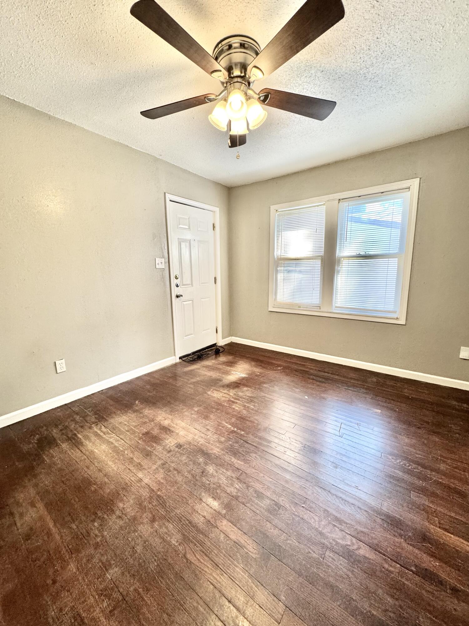 2421 22nd Street, Unit FRONT Lubbock, TX 79411 - Photo 15 of 17 an empty room with wooden floor chandelier fan and windows