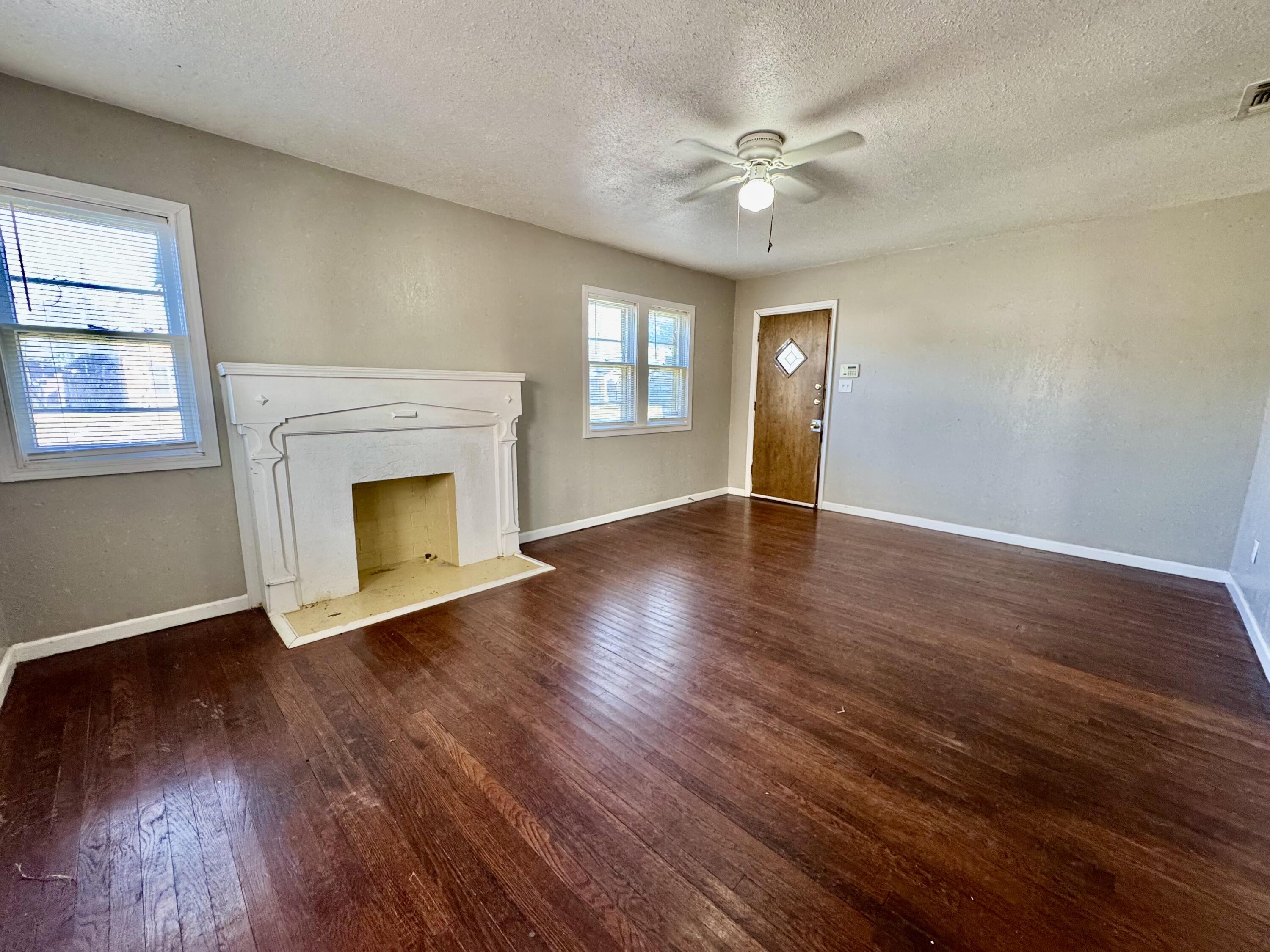 2421 22nd Street, Unit FRONT Lubbock, TX 79411 - Photo 4 of 17 an empty room with wooden floor fireplace and windows