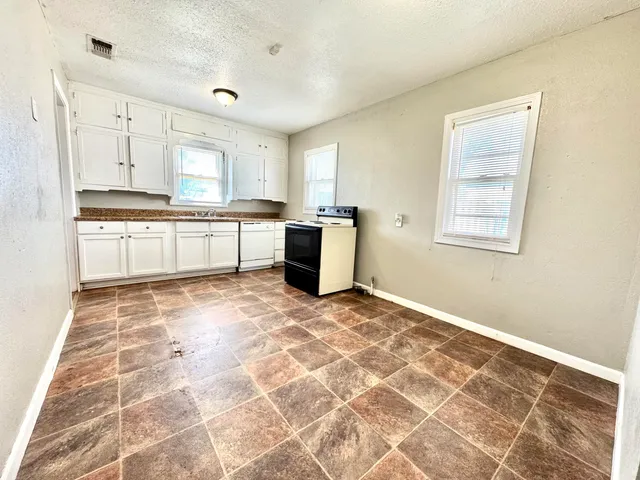 a large white kitchen with a stove a sink and a window