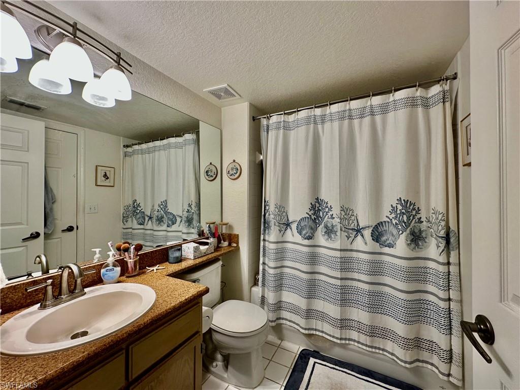 4700 St Croix Lane, Unit 335 Naples, FL 34109 - Photo 12 of 31 a bathroom with a sink a toilet a mirror and shower curtain