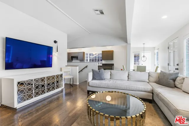 a living room with furniture a flat screen tv and kitchen view