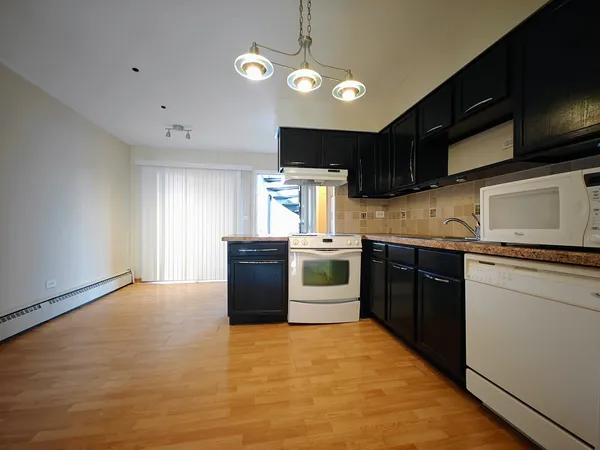 a kitchen with stainless steel appliances granite countertop a sink a stove top oven and white cabinets