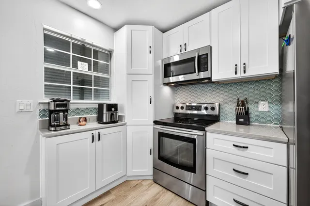 a kitchen with stainless steel appliances white cabinets and a stove top oven