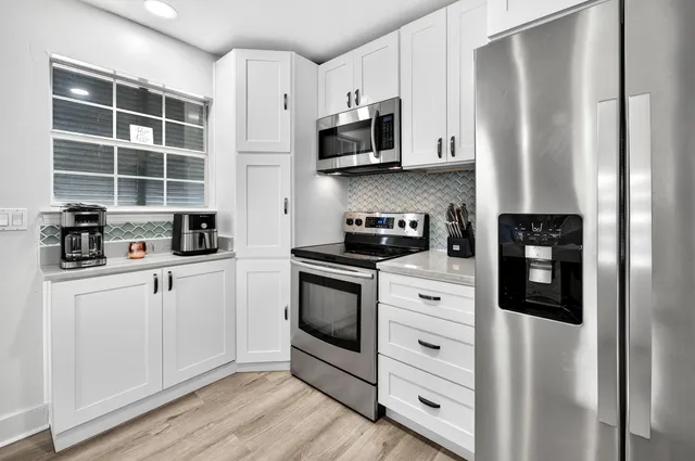 a kitchen with stainless steel appliances granite countertop a sink refrigerator and cabinets