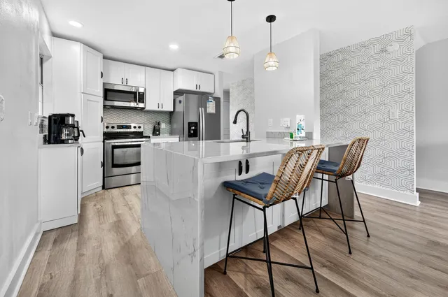 a kitchen with stainless steel appliances a refrigerator a stove top oven a sink dishwasher and a dining table with wooden floor