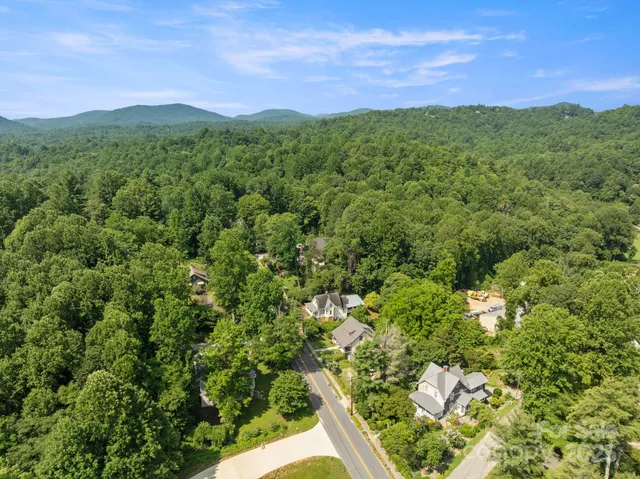 a view of a lush green forest with a house in the background