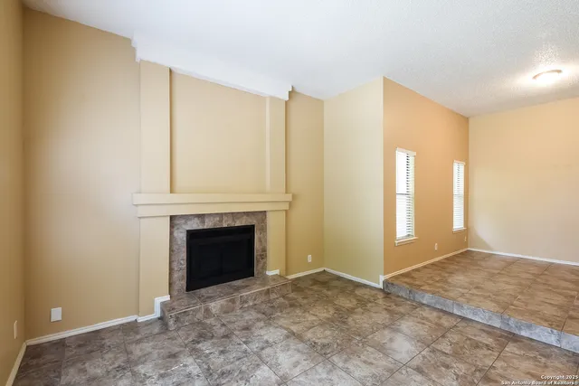 a view of an empty room with window and fire place