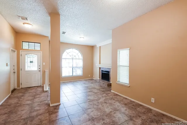 an empty room with windows and fireplace