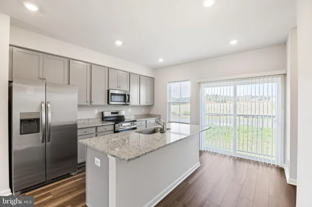a kitchen with stainless steel appliances granite countertop a stove a sink and a refrigerator