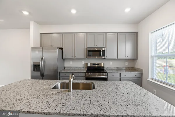 a kitchen with stainless steel appliances granite countertop a sink stove microwave and refrigerator