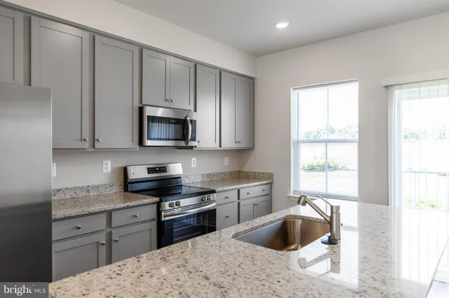 a kitchen with stainless steel appliances granite countertop a sink a stove and microwave