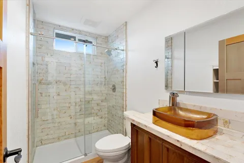 a bathroom with a granite countertop sink toilet a mirror and shower