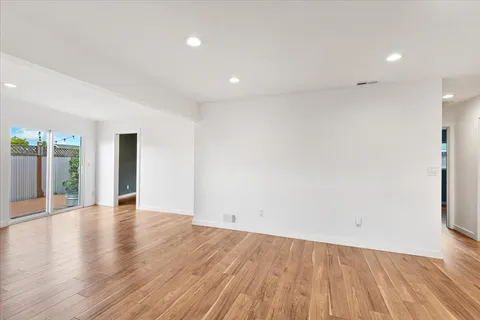 an empty room with wooden floor and natural light